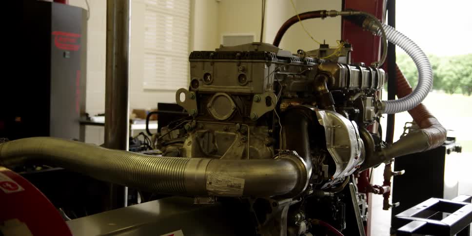 Machinery with pumps and tubes sits in workshop with open side showing outdoors