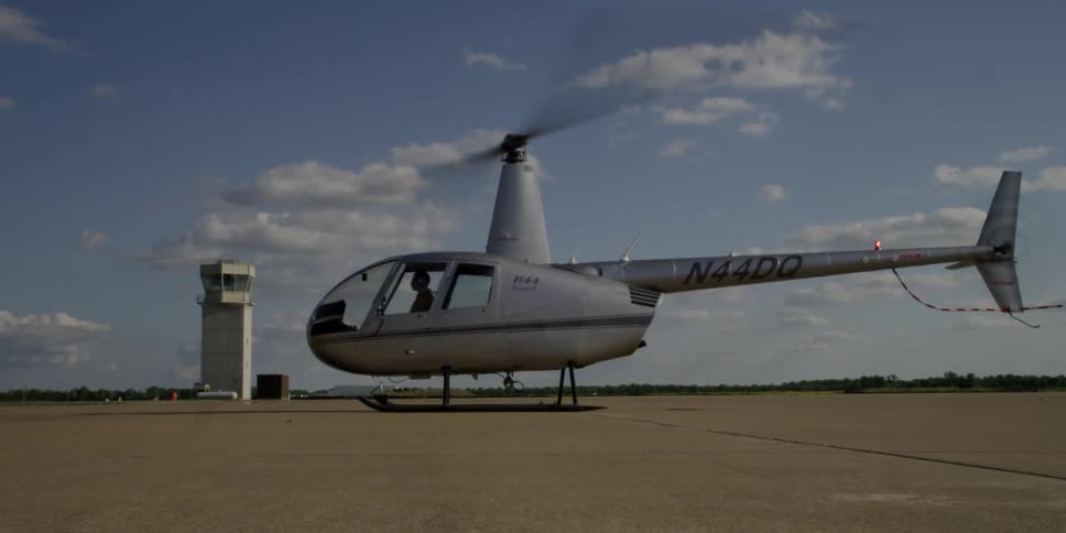 Helicopter sits on the airfield as its blades spin