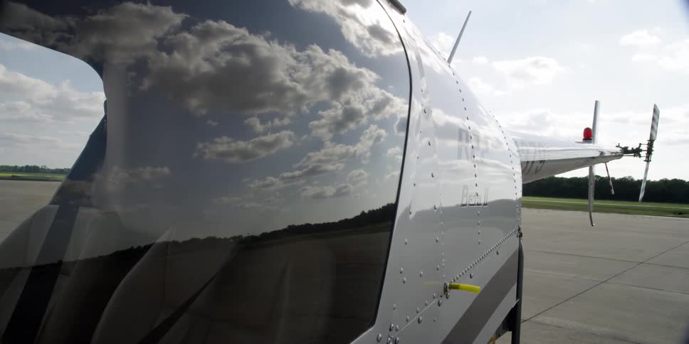 Clouds reflecting off a helicopter at an airfield