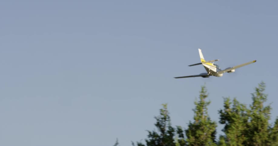 An airplane flies over a forested area
