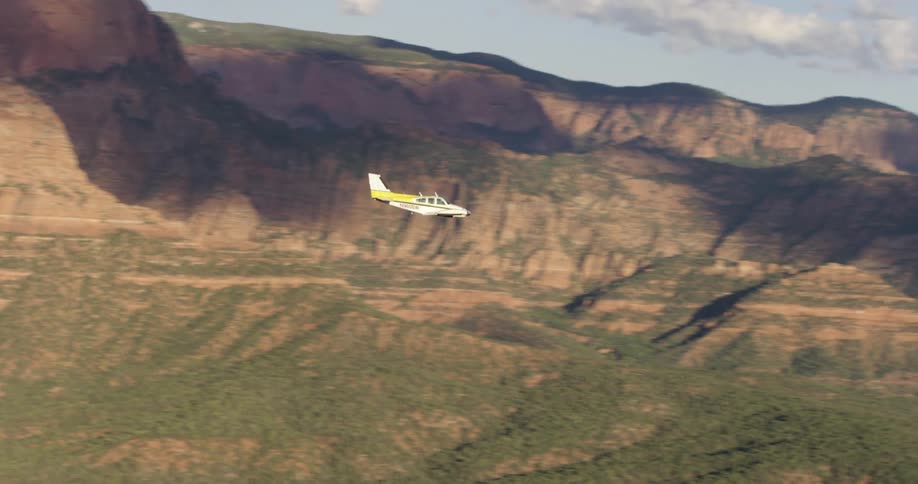 A small airplane flies over a canyon