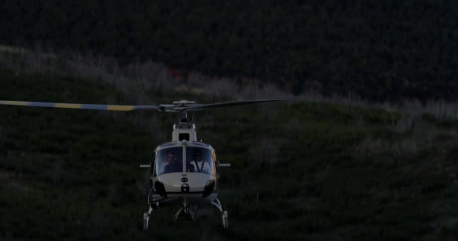 A helicopter is flying above the forest