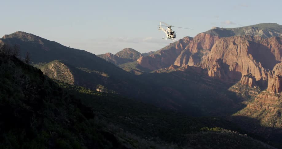 A helicopter flying with mountains in the background