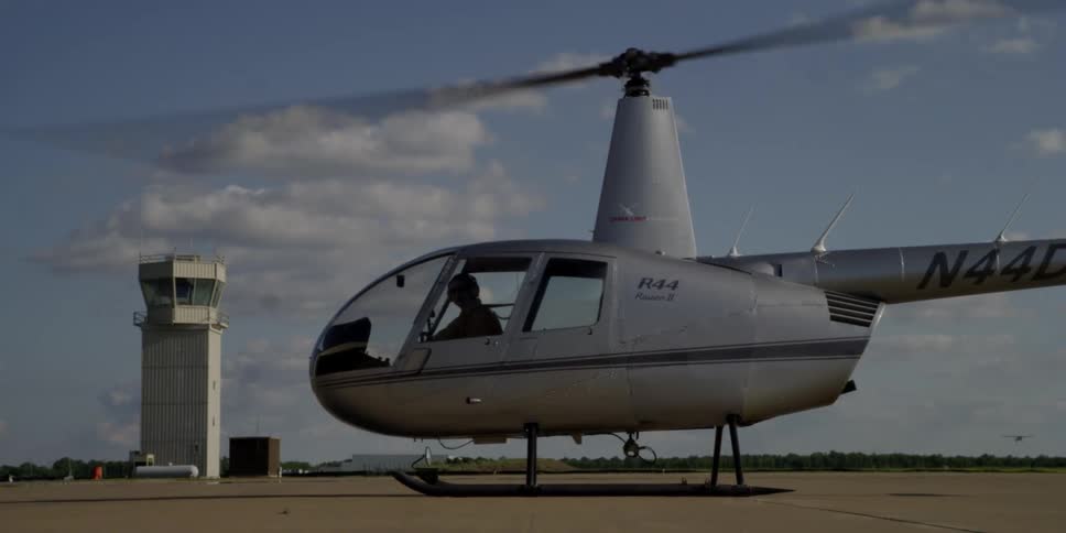 A man is sitting in a parked helicopter