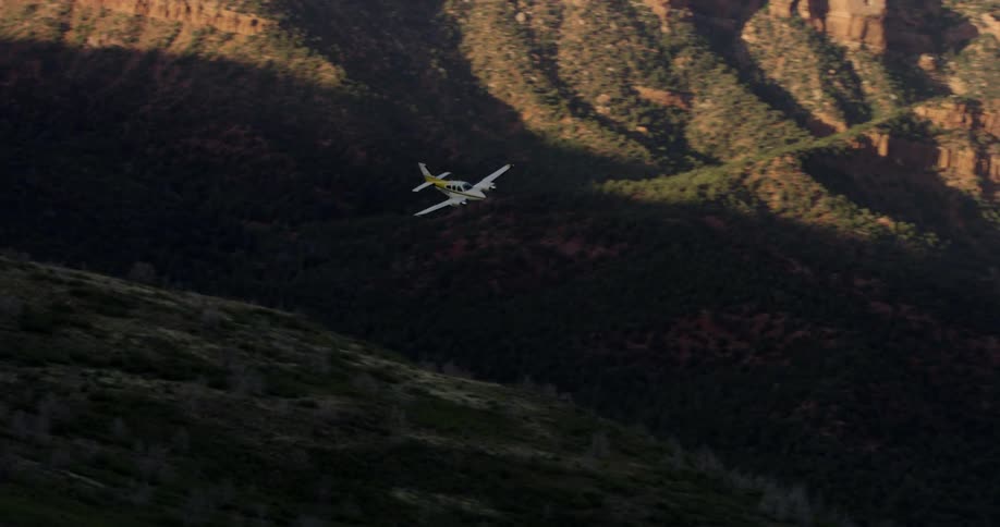 An airplane flies over a mountain valley