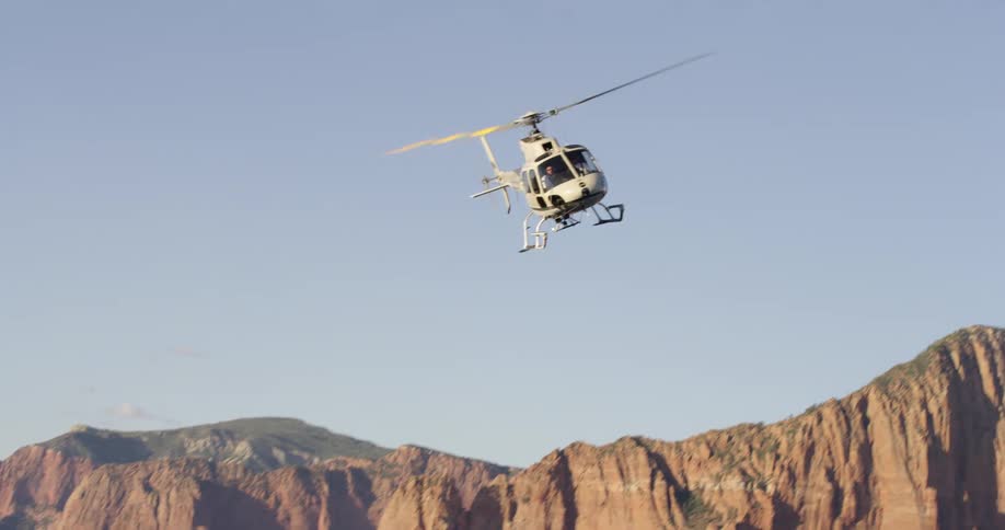 A helicopter flying over flat topped mountains in the badlands