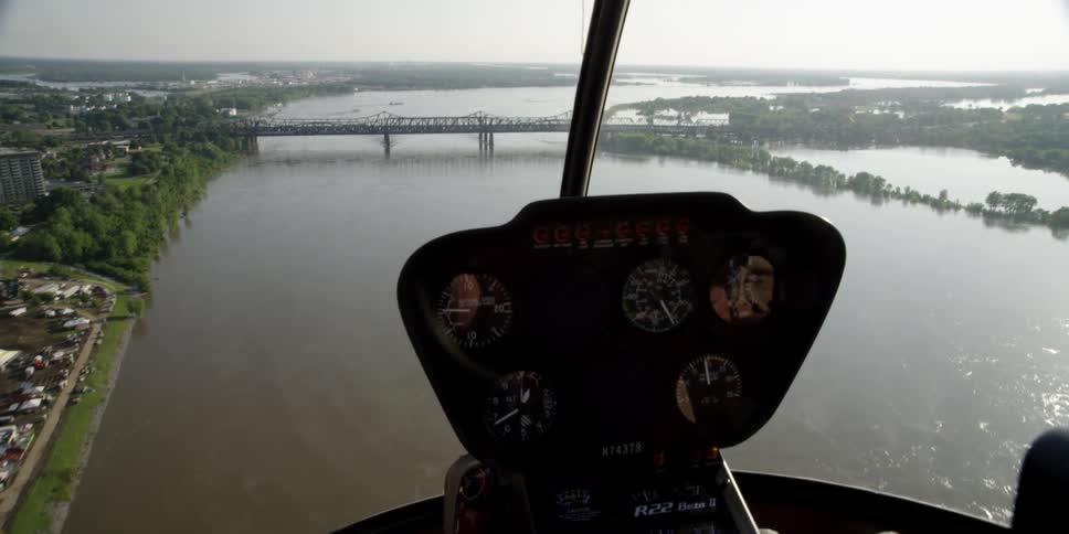 A helicopter flies over a river off the coast of a city