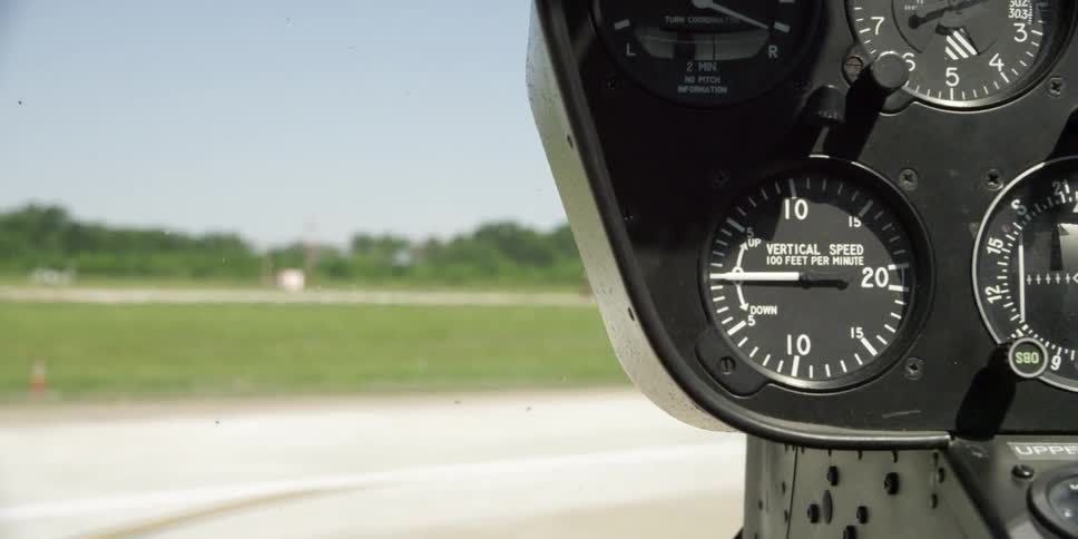 Close up of a helicopter cockpit controls while hovering over an airfield