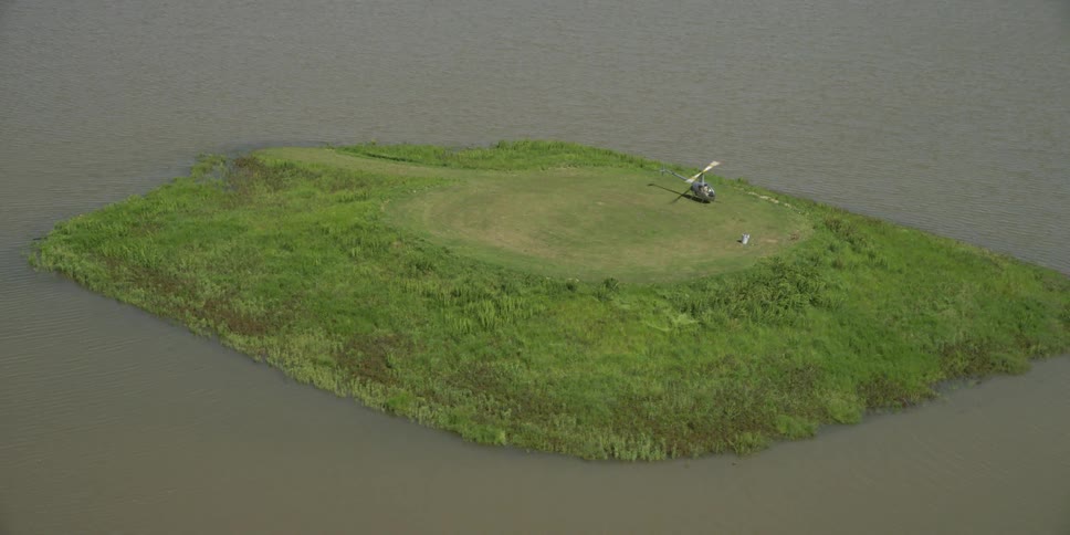 A helicopter with its propellers turning on a small island