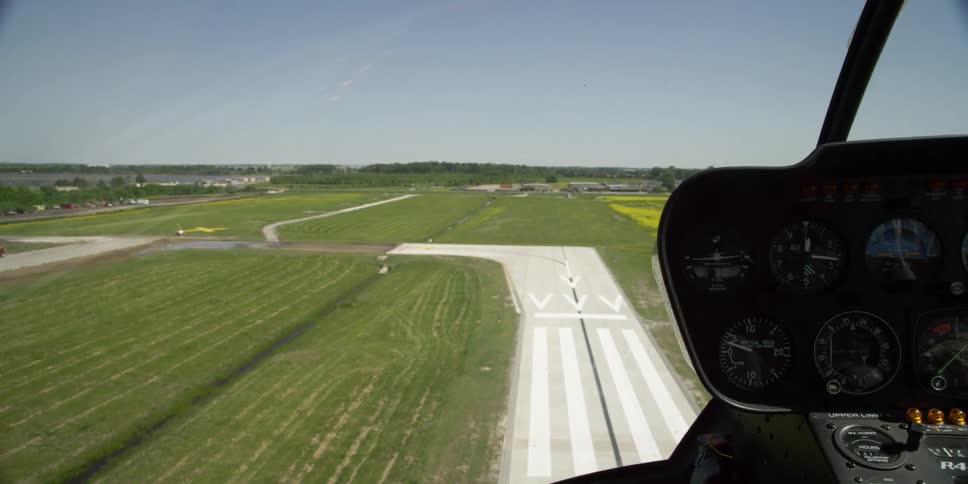 A helicopter flies over a concrete runway at an airport