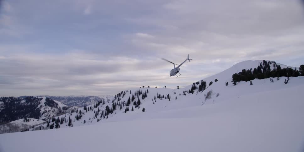A helicopter flies over a snow covered nature area