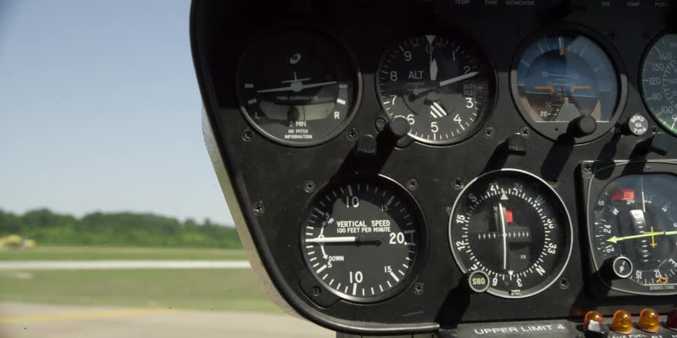 A helicopter gauges with a grassy field trees and the sky in the background