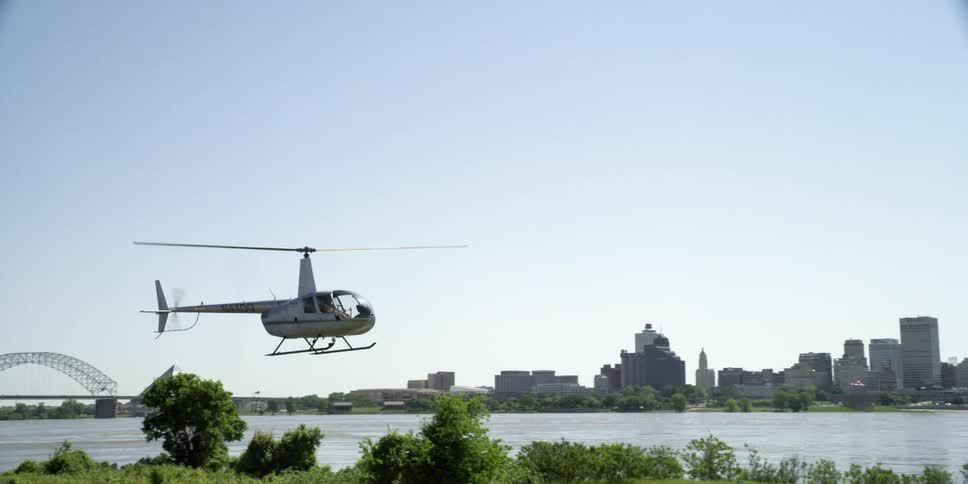 A helicopter flies over a river near a city