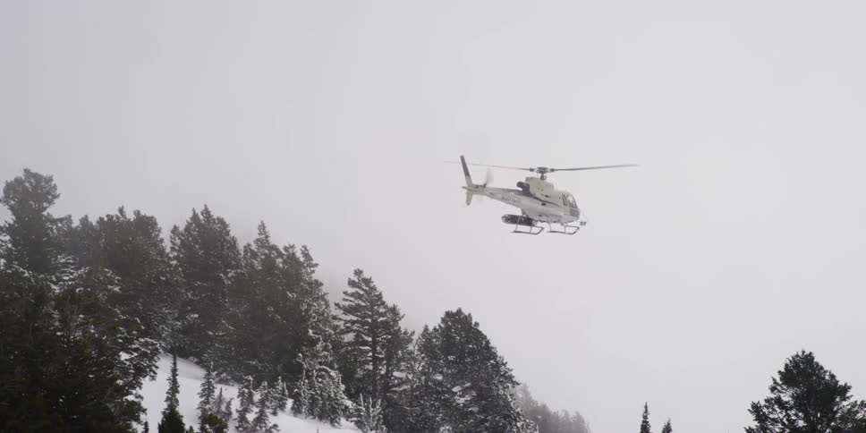A helicopter flying above snow covered hills