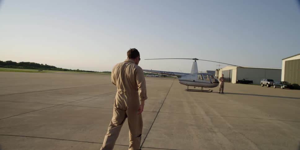 Pilot walking towards a helicopter at an airfield