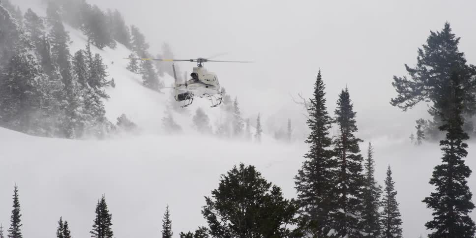 A helicopter is driving above the snowy ground