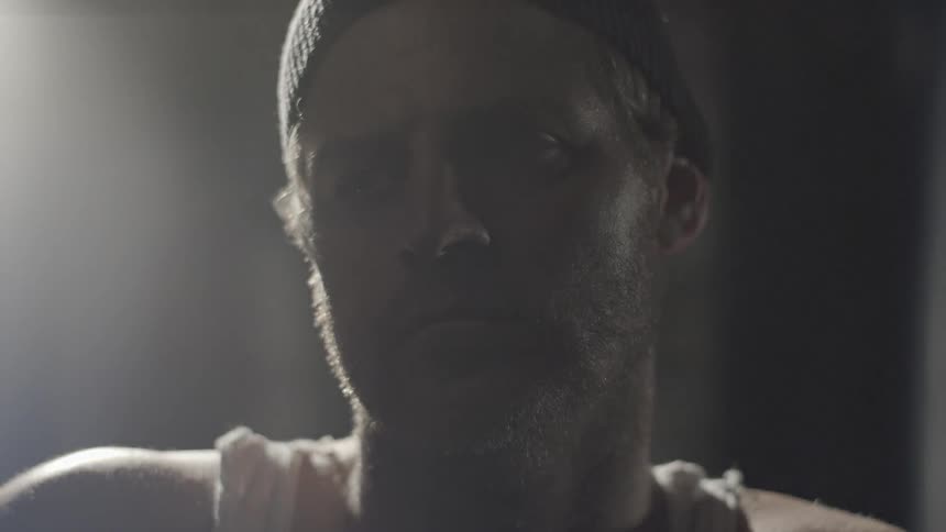 A man is looking forward in a dark room as a light blinks