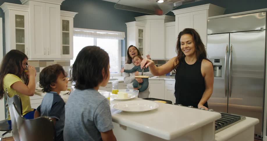 A woman serves pancakes to her children
