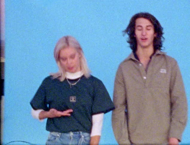 Teenagers hold skateboards in front of a photography backing