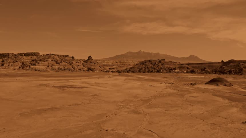 Flat sand in a desert gives way to a canyon with tall plateaus Mars