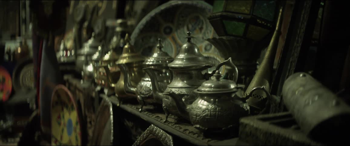 Rows of metal teapots sit on a dusty shelf in a store