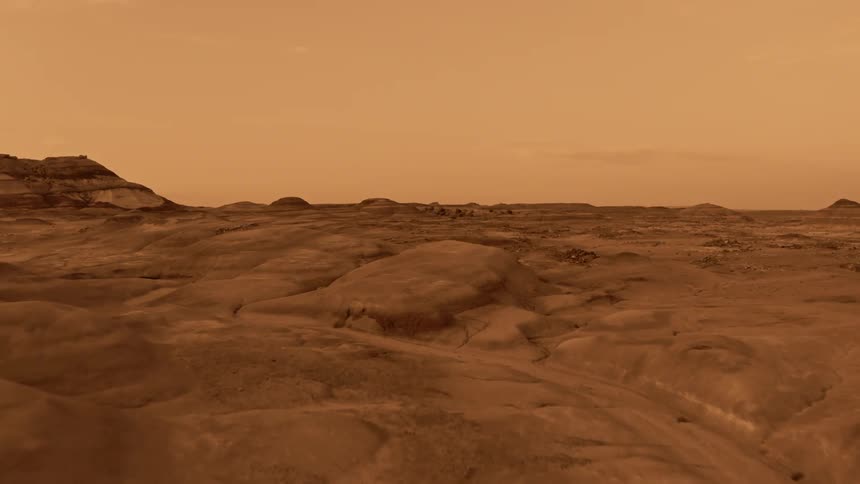 A desert terrain with a dry riverbed and mountains and mounds