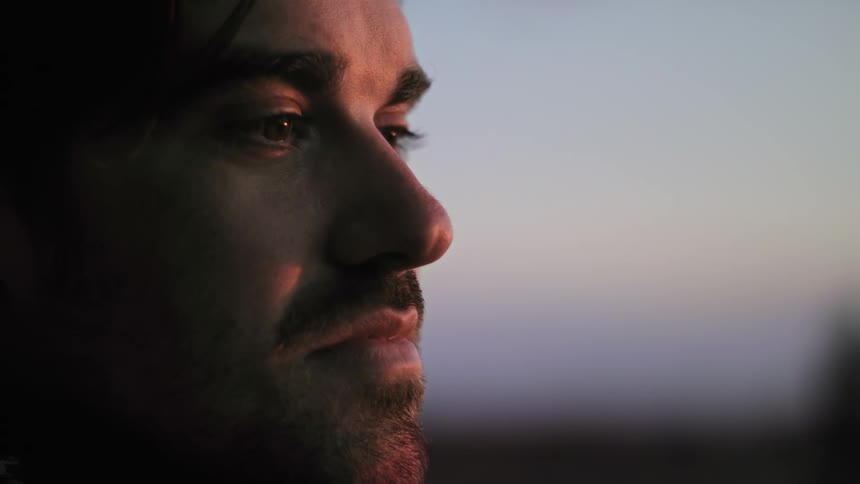 A man is standing outdoors at dusk