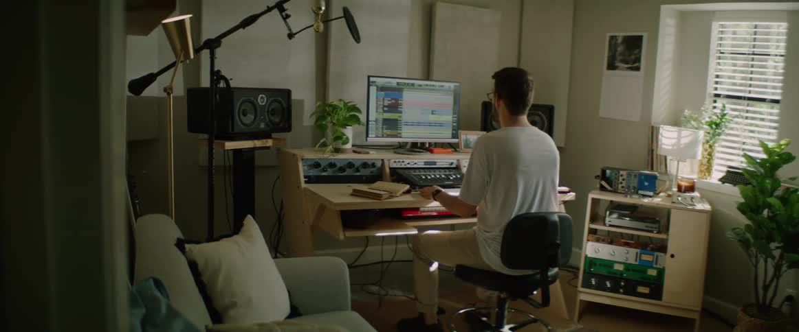 Man sits on a task chair at a desk and works on a computer