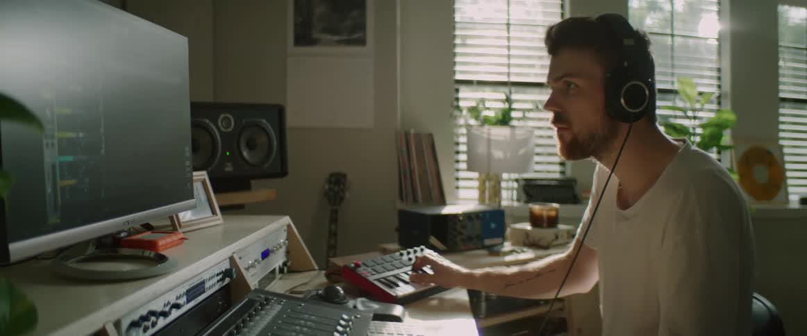 A man moves his head to the beat of music hes creating on a keyboard and computer