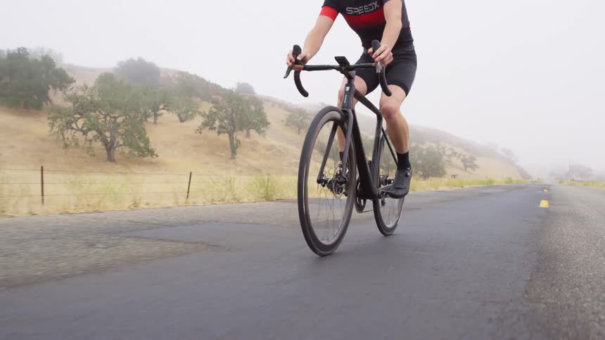Man wearing shorts rides a bicycle on the road near the hills