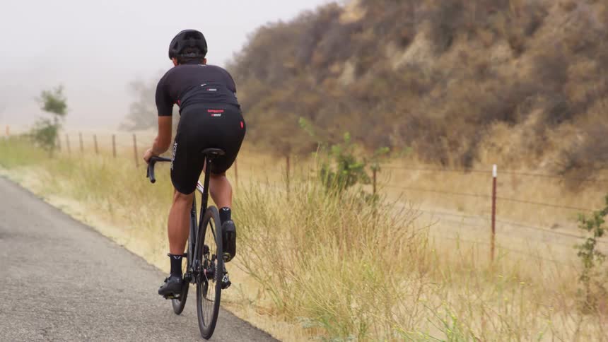 A bicyclist rides down a road in a rural area