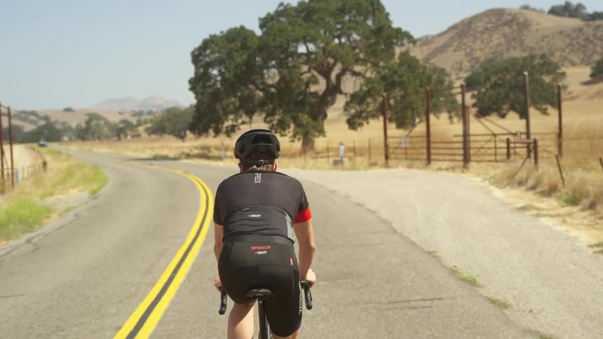 A cyclist traveling down a road through the countryside on a bicycle