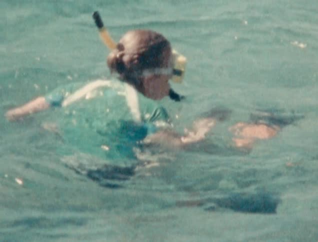 A young white girl swims in water with a snorkel
