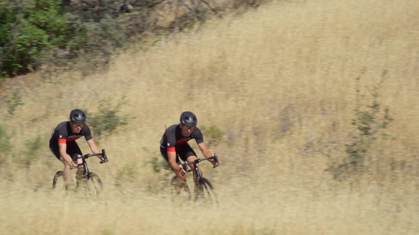 Cyclists with cycling helmets and cycling jerseys ride bicycles on a road