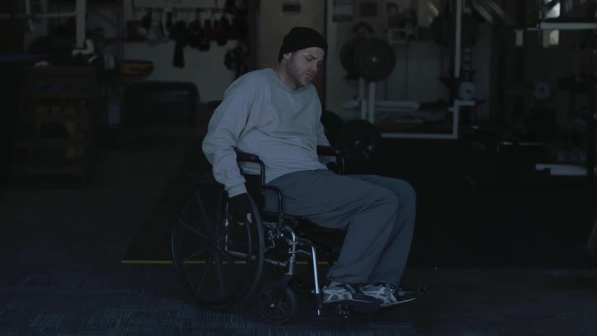 A man sits in a wheelchair and flicks a cigarette