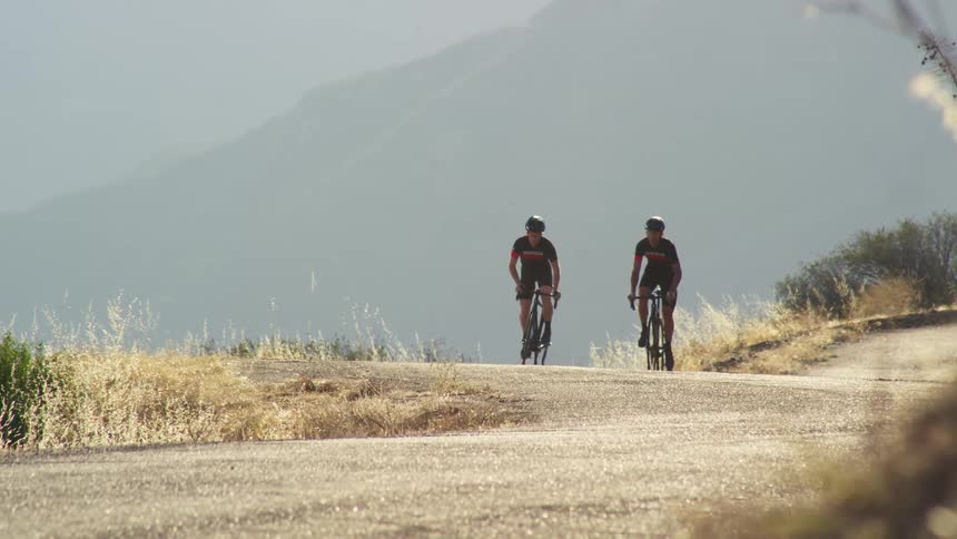 Two men are riding bicycles outdoors