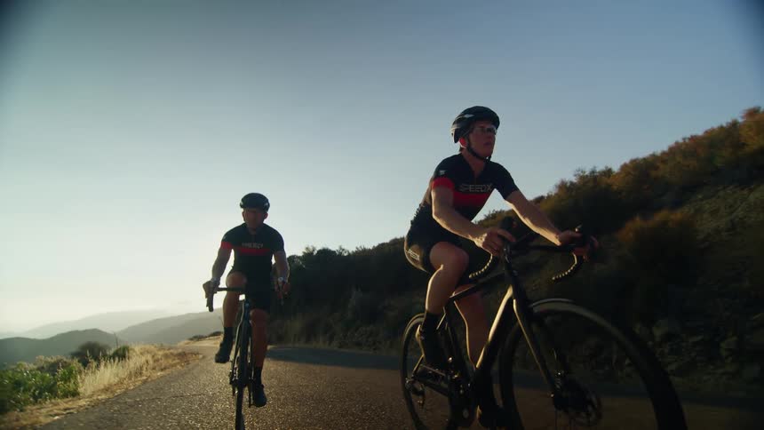 Two bicyclists ride their bikes on a rural road