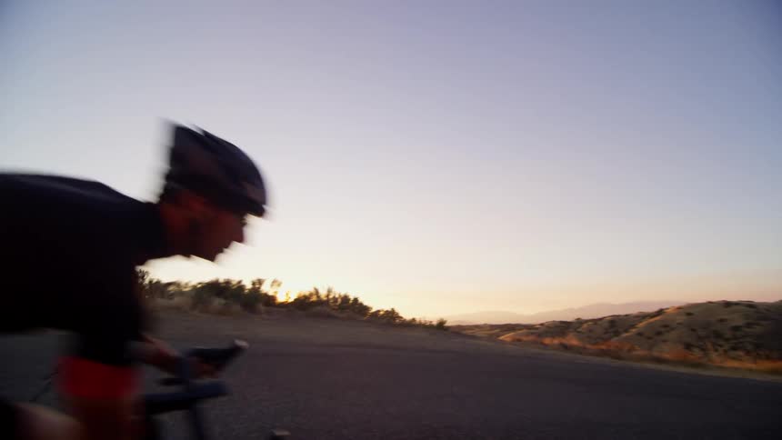 Cyclists cycle and corner at speed a mountain road at sunset