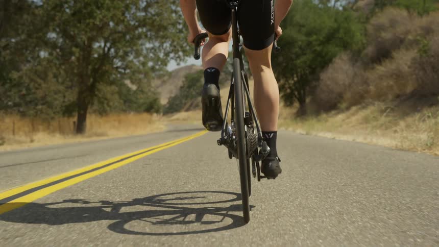 A man is bicycling outdoors on a open road