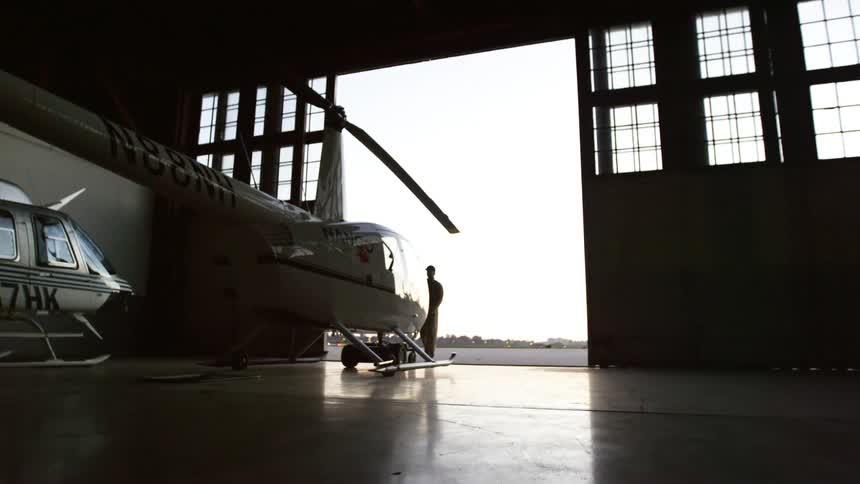 Person pulling out a helicopter outside from the hangar
