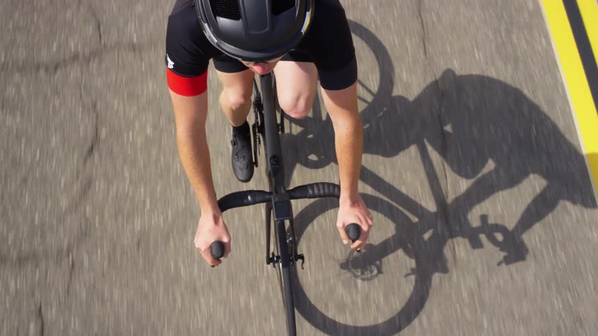 Cyclist wearing helmet rides bicycle down a road