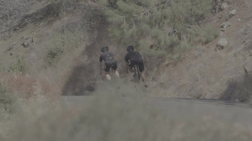 The people ride their bicycles on the small trail