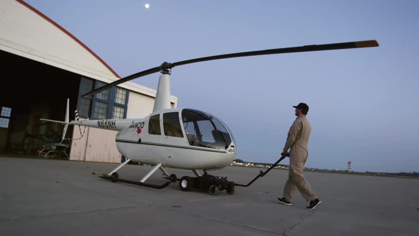 A man is moving a helicopter outdoors