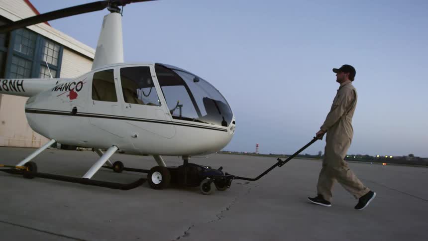 A man is pushing a helicopter outdoors