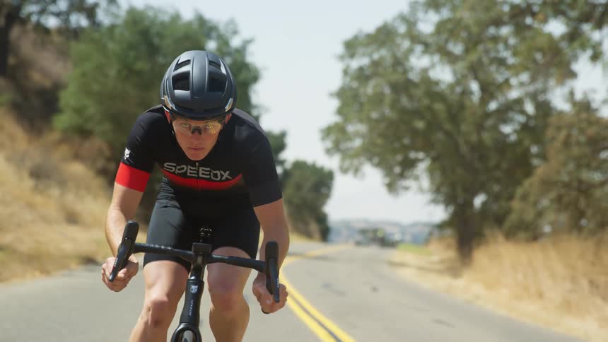 A bicyclist pedals down a road in a rural area