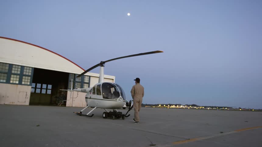 A man pulls a helicopter across the tarmac