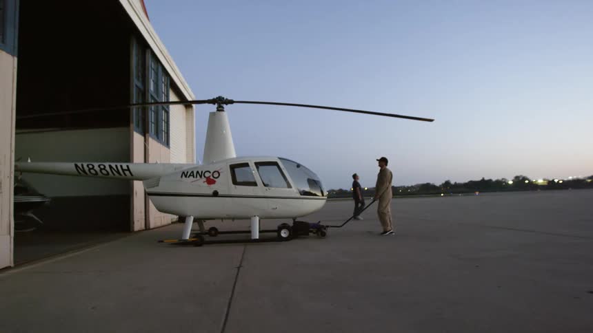 A man guides a helicopter in to a shop