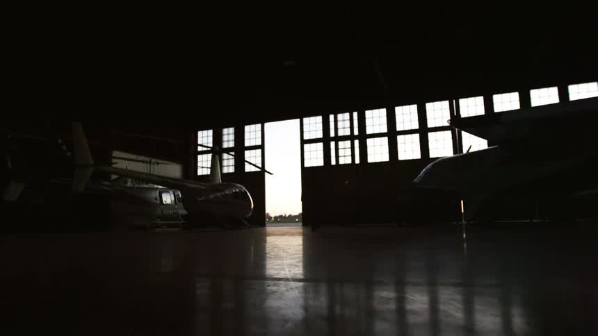 A man walks into a hangar containing aircraft