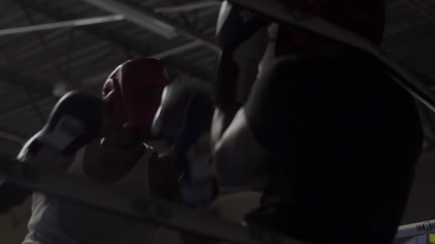 Two boxers train in a ring wearing amateur gear