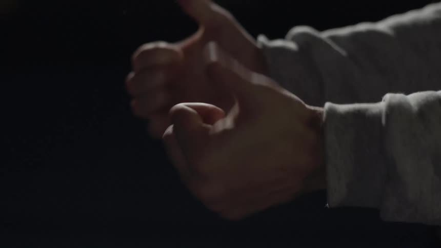 Close up of two hands moving around in a dark area